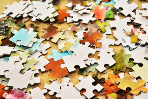 Jigsaw puzzle pieces scattered on a wooden tabletop