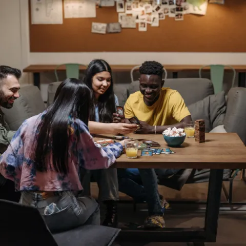 Group of four young adults playing a card game on a table.