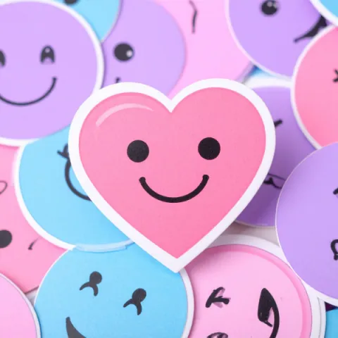 Collection of smiley-face stickers with a heart-shaped sticker in the center.
