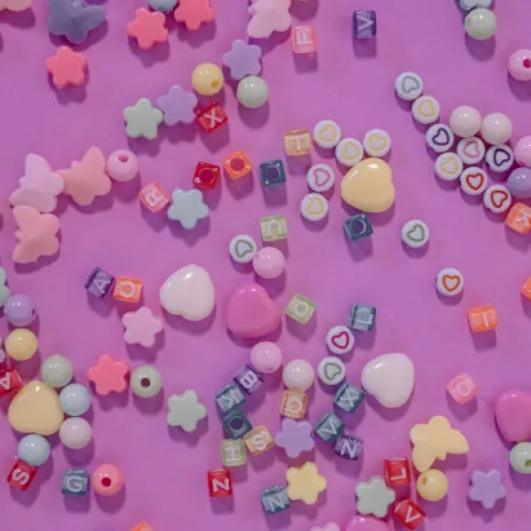 Collection of beads spread over a pink background.