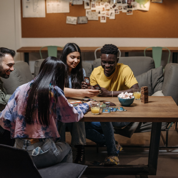 Group of four young adults playing a card game on a table.