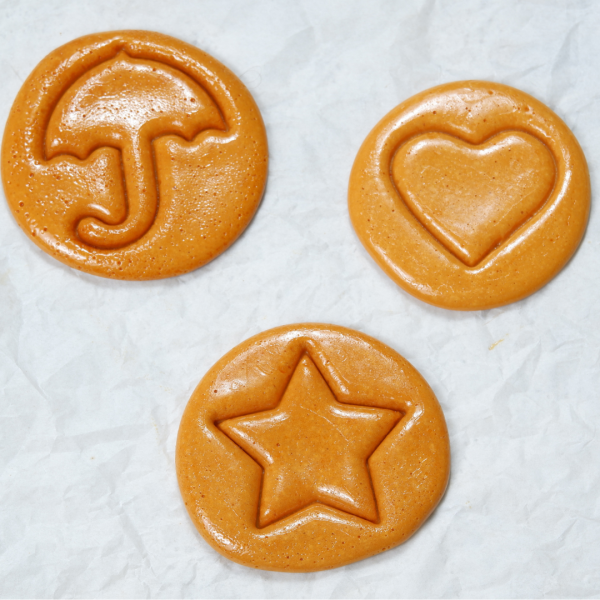 three circular dalgona with an umbrella, heart, and star design